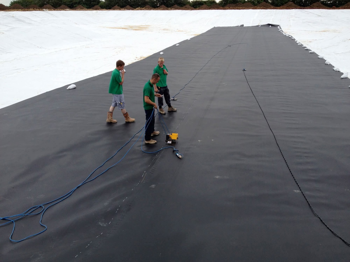 A roll of HDPE liner being lowered into position for a lake construction