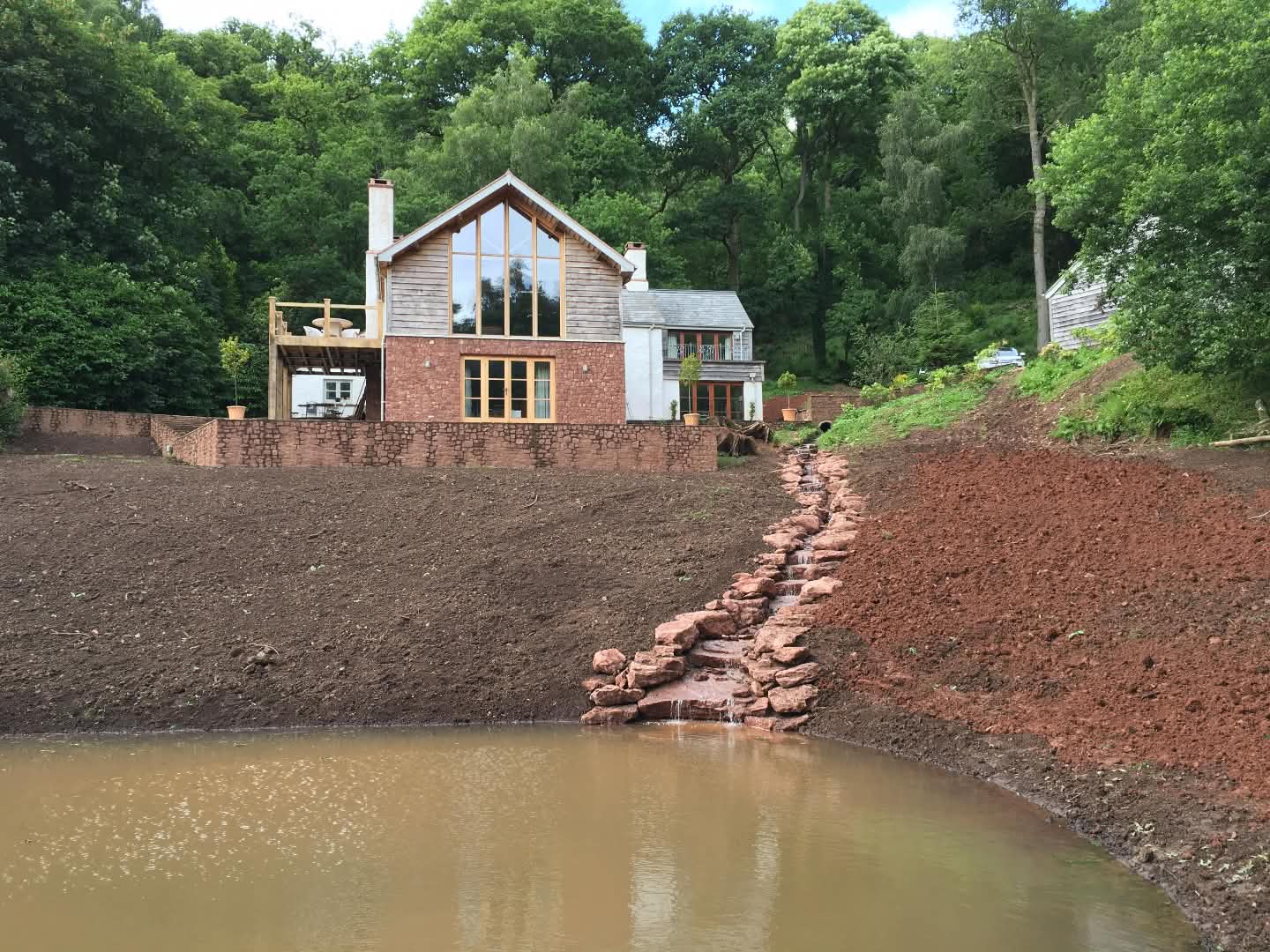 long stepping-down stone waterfall along the side of house into lake