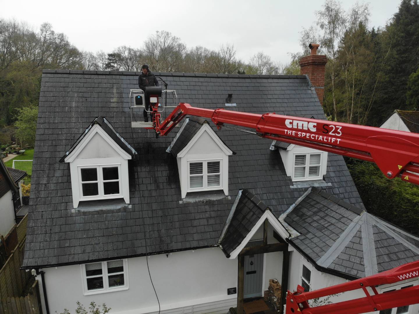 Man washing the roof of a beautiful house