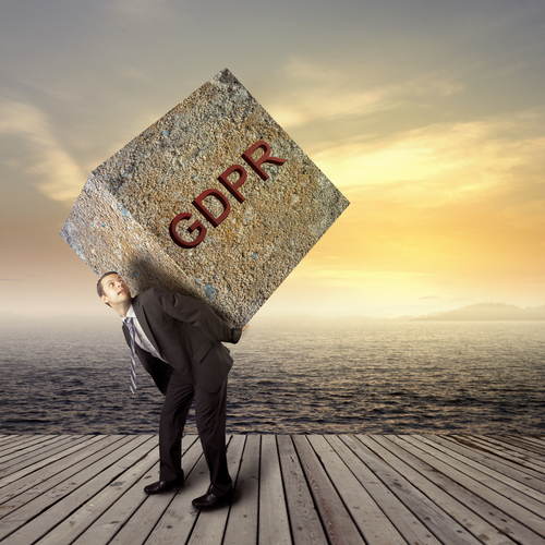 Businessman carrying heavy stone block with GDPR written on it