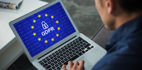 Person working on laptop with GDPR displaying on the screen against EU flag background