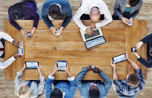 Office workers around a table using digital devices