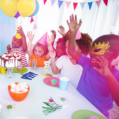 Children at birthday party sat on table with deserts