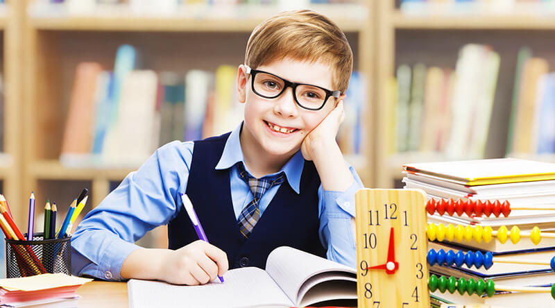 happy young boy writing in textbook