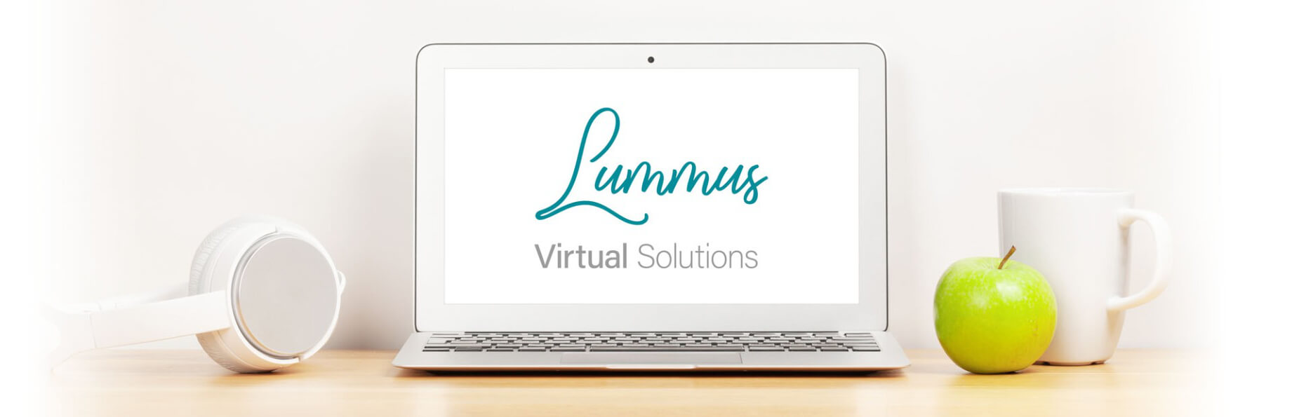 The logo of virtual assistant, Kerry Lummus on a laptop screen. Beside it is a mug, apple and a pair of headphones.. 