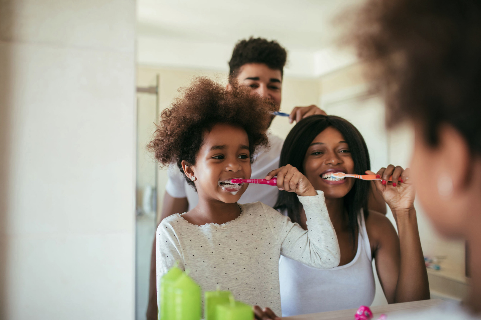 family brushing teeth in front of mirror