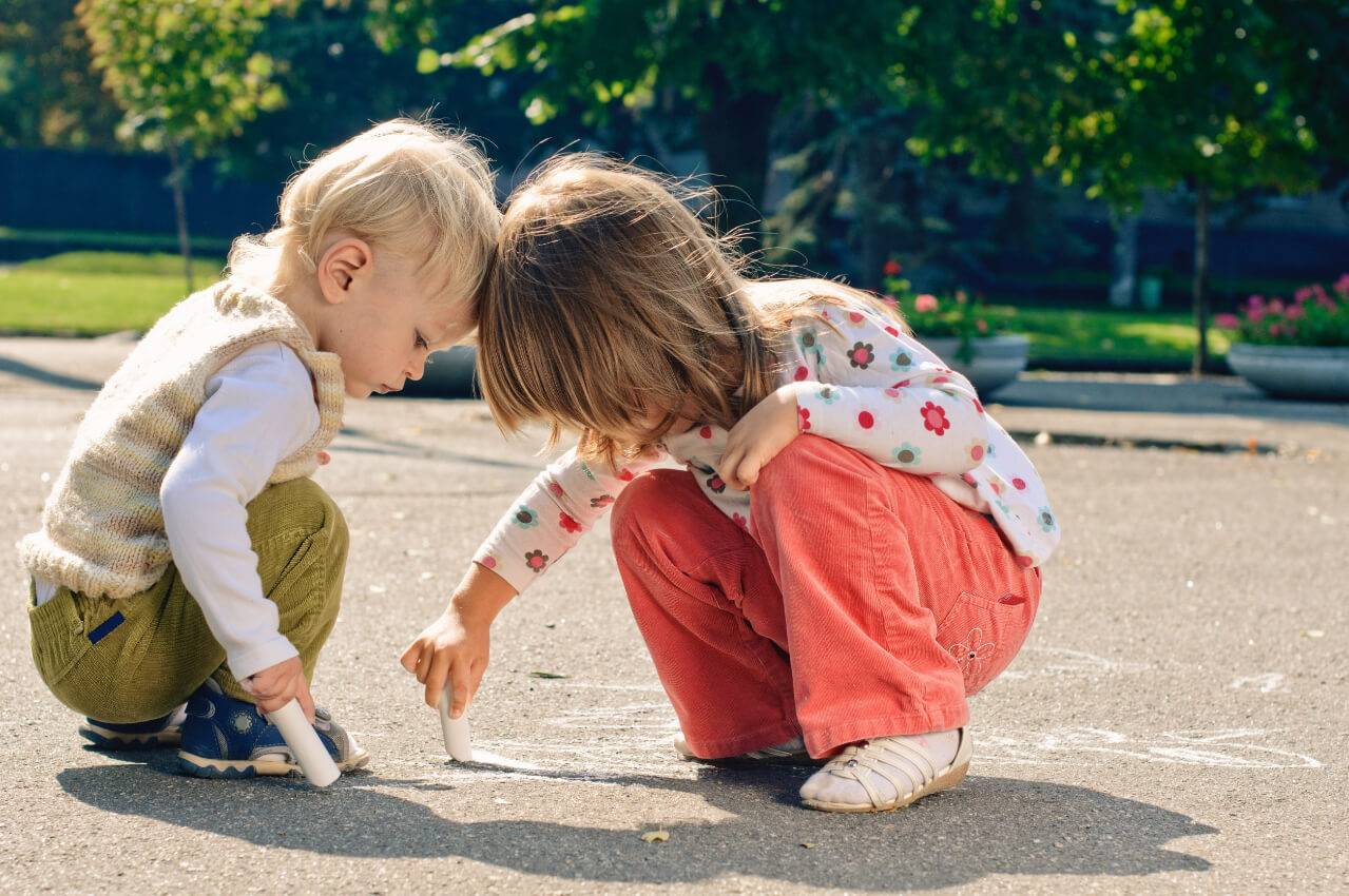 Two young children playing with chalk
