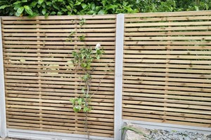 Modern type of fence panels for a garden fence with planed wooden horizontal batons, nailed to a ridged wood panel frame and pressure treated.
