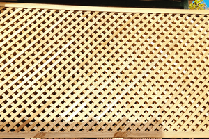 A series of equally spaced planed narrow wooden batons securely fixed in a  rebated frame. Half are diagonally laid evenly spaced, with the other half laid in the opposing diagonal direction.