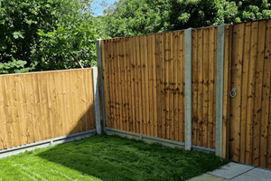 This pressure treated panel has vertical tapered palings which overlap the neighbouring board and nailed after the overlap to square cut fence rails with stainless steel nails. A wooden cap is nailed on the top of the panel to protect the end grain of the palings.