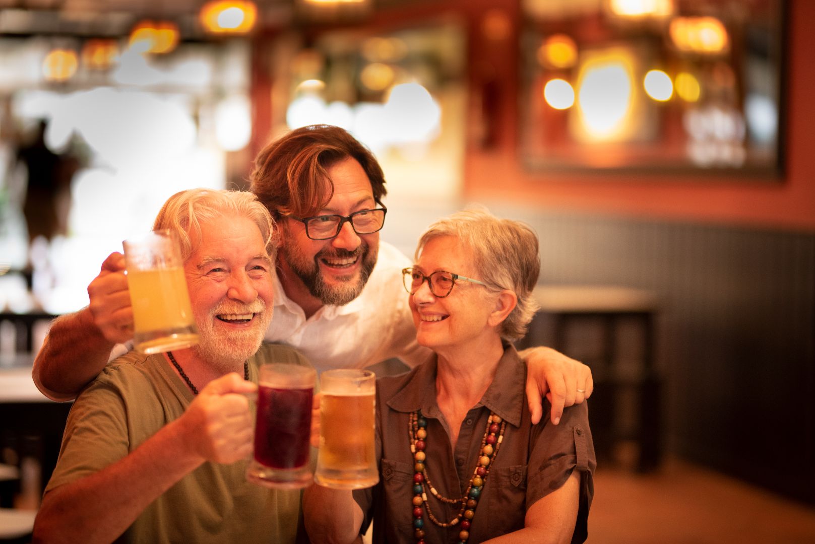 three people toasting with drinks in bar