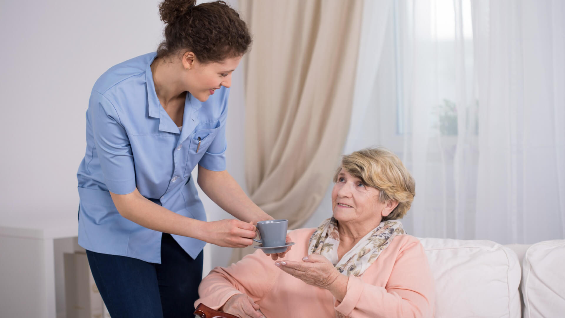 Carer giving woman cup of tea