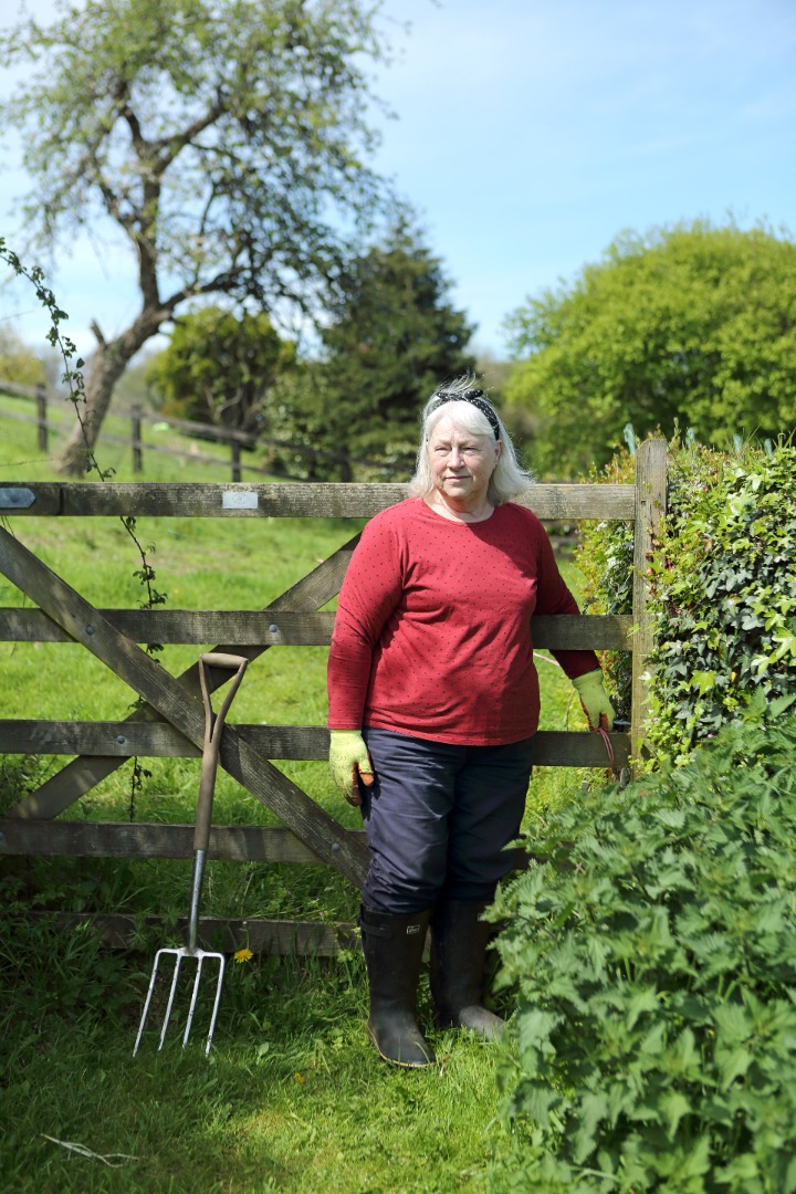 Woman gardening standing by a gate