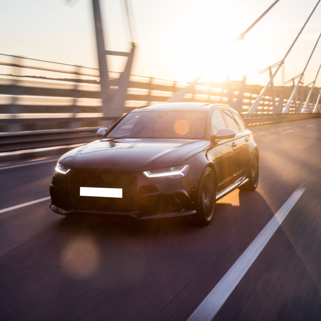 Black sedan on bridge in sunset