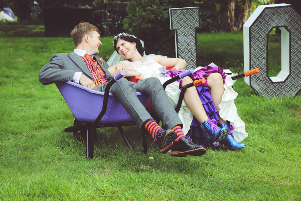 bride groom laughing in wheelbarrow