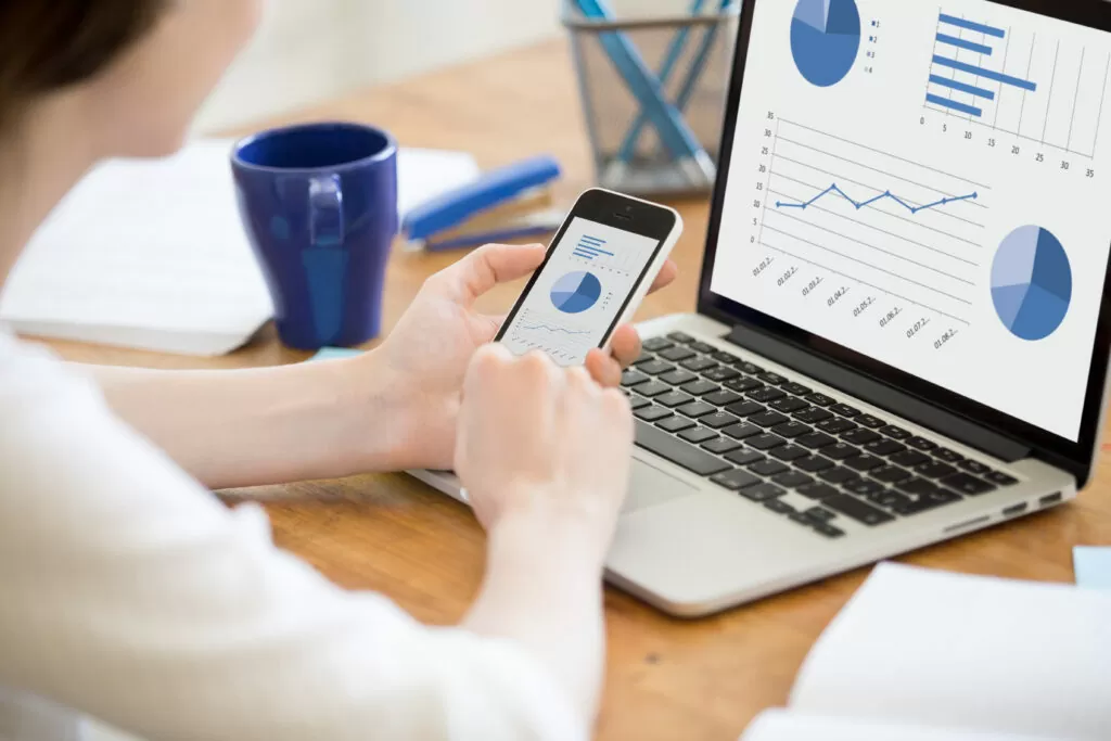 Woman holding a phone with a graph on it, processing accounts invoices