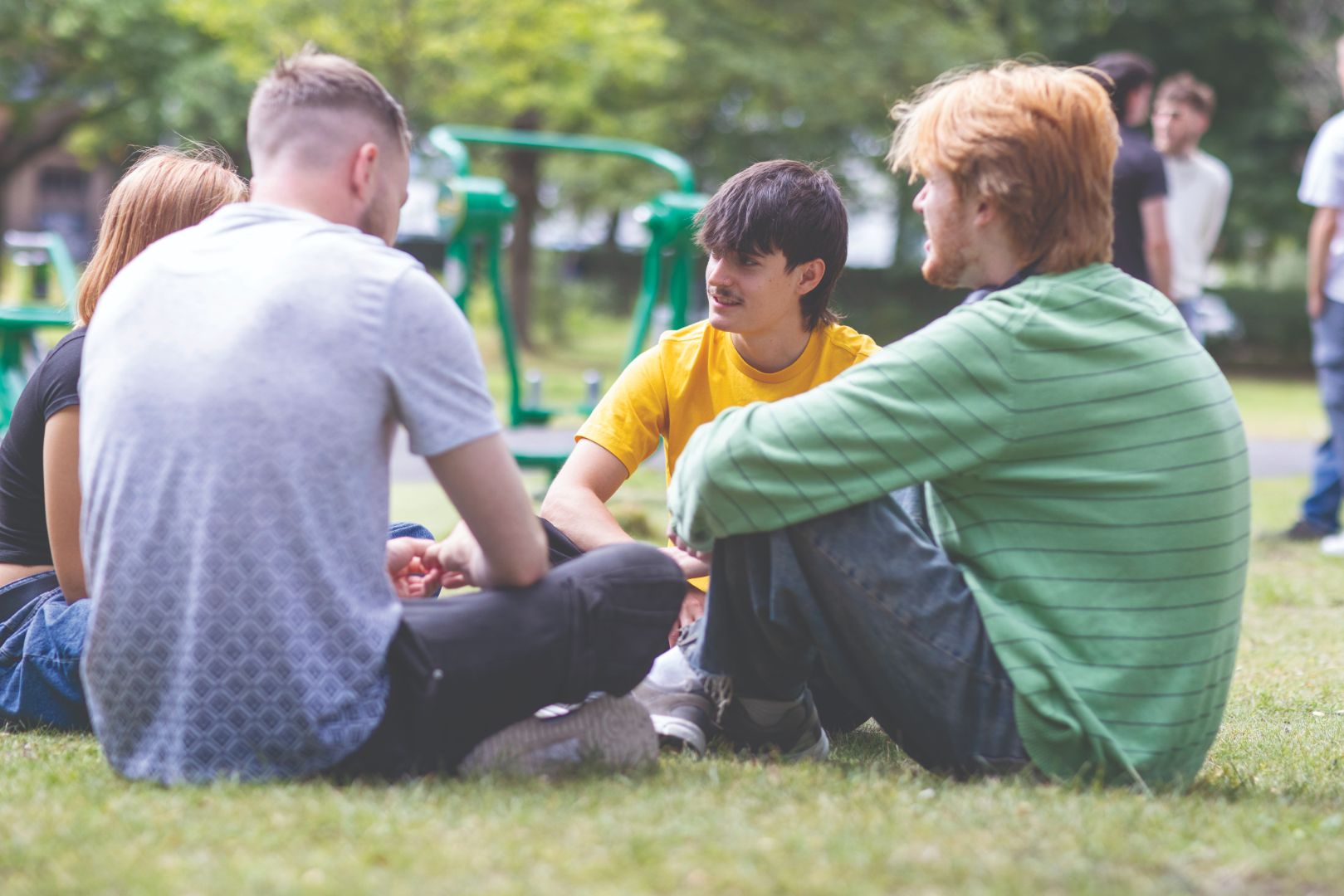 Teenagers sitting on the grass in a circle