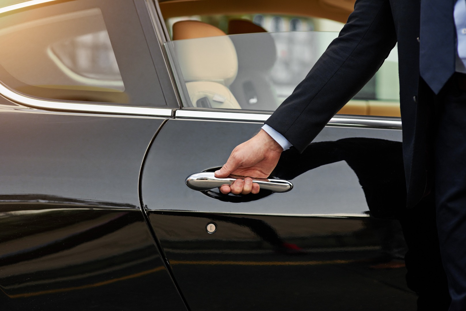 Male chauffeur opening a car door