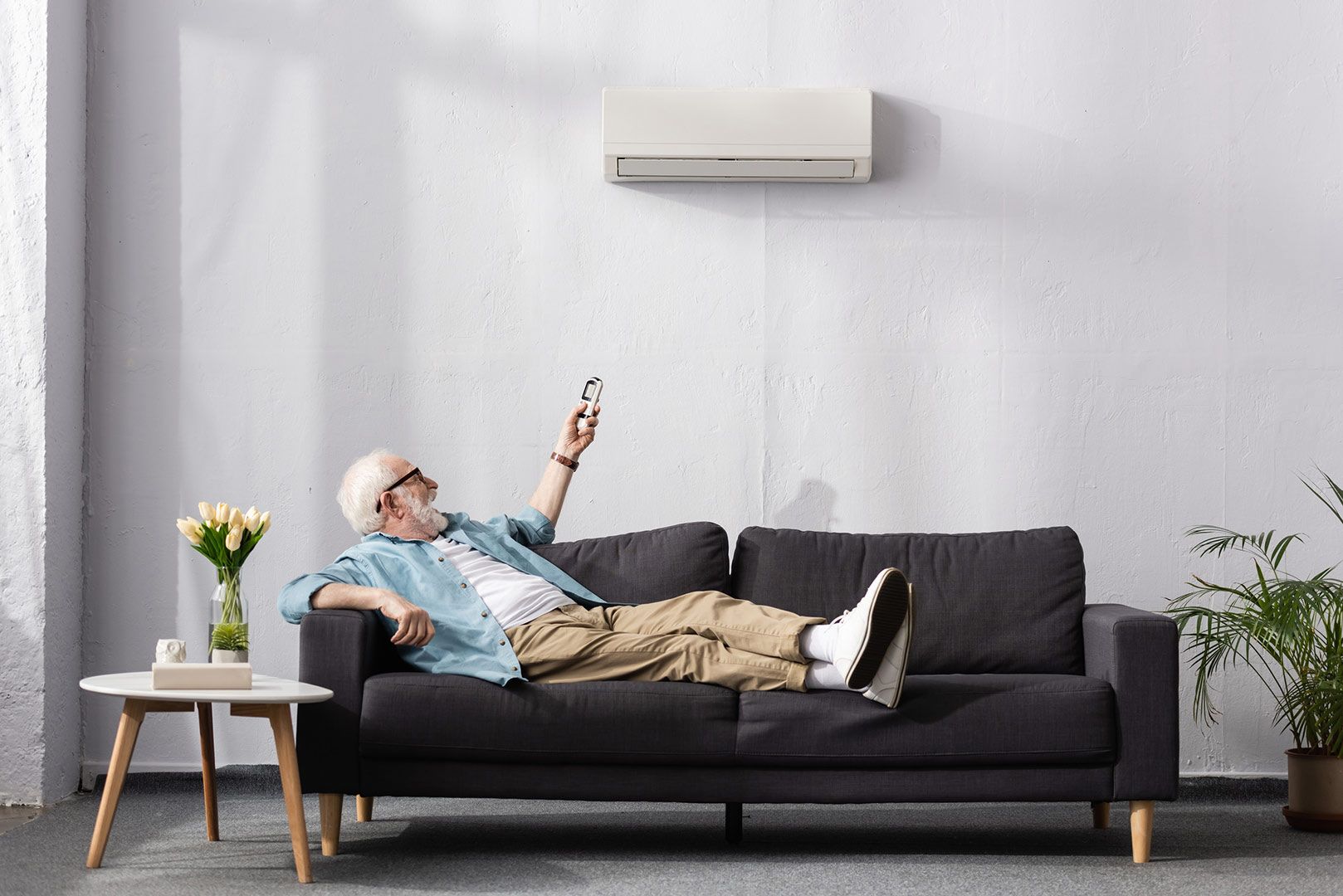 Man on the sofa using the air conditioner