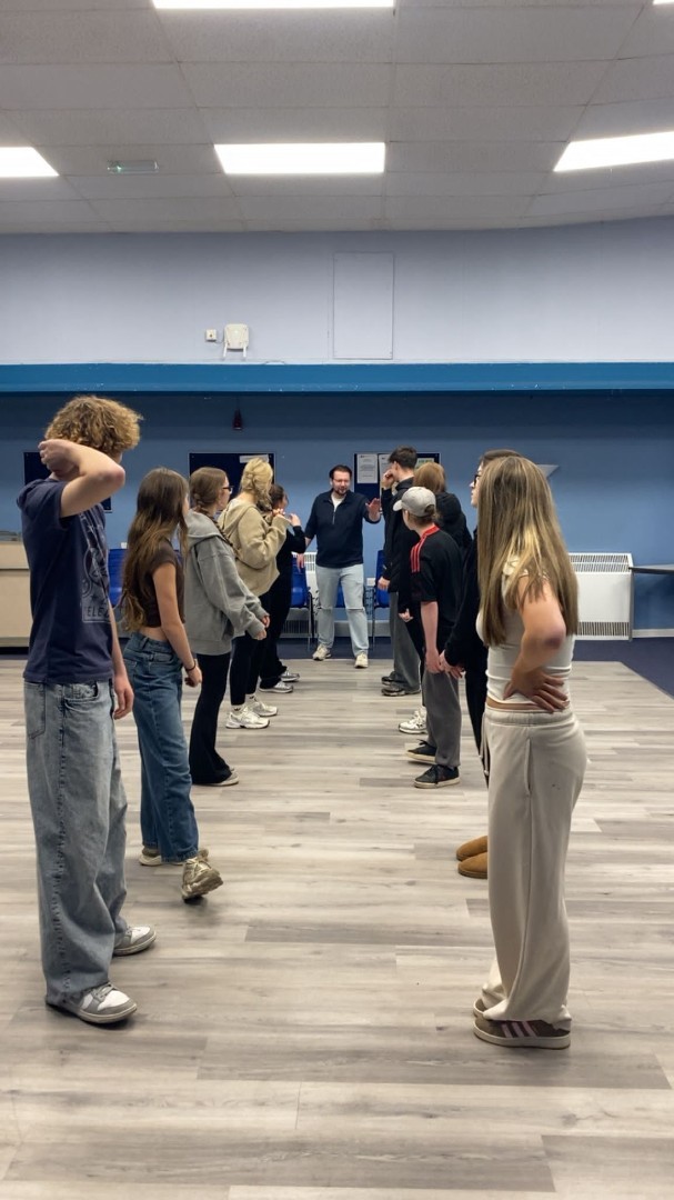 Teens act out scene with teacher