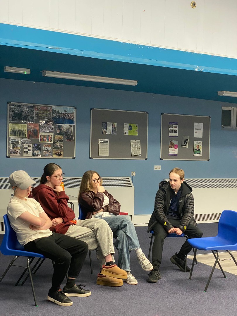 Teens sitting on chairs and watching carefully