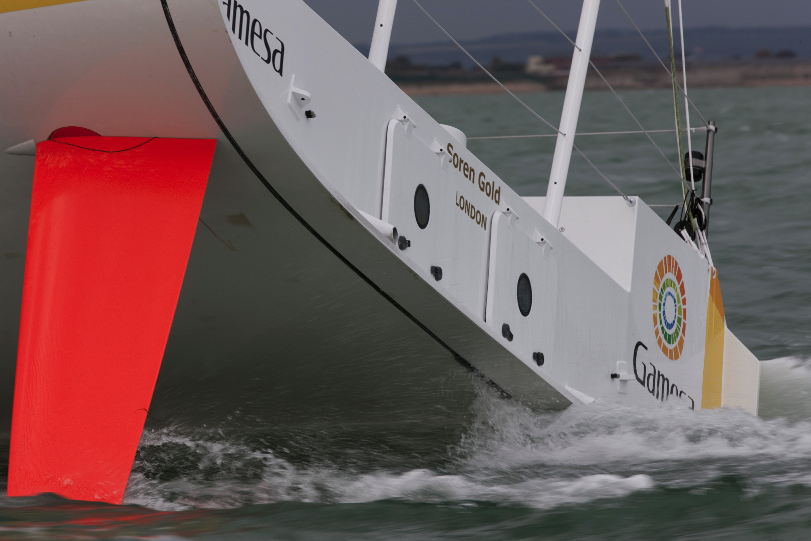 This is Gamesa, an IMOCA Open 60 design with an interceptor deployed, an innovation for sailing yacht design by naval architects Owen Clarke Design. This is a trim control device allowing  yacht to have two modes, effectively two rocker profiles: with a considerable reduction in hull drag across a wide speed range in flat water and  bow up trim, with high manoeuvrability and safety in medium to large waves.